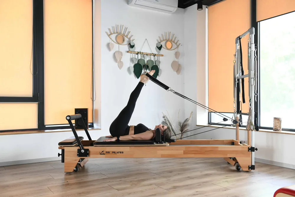Cursantă care lucrează pe Reformer cu turn, în sala privată a studioului Venusao